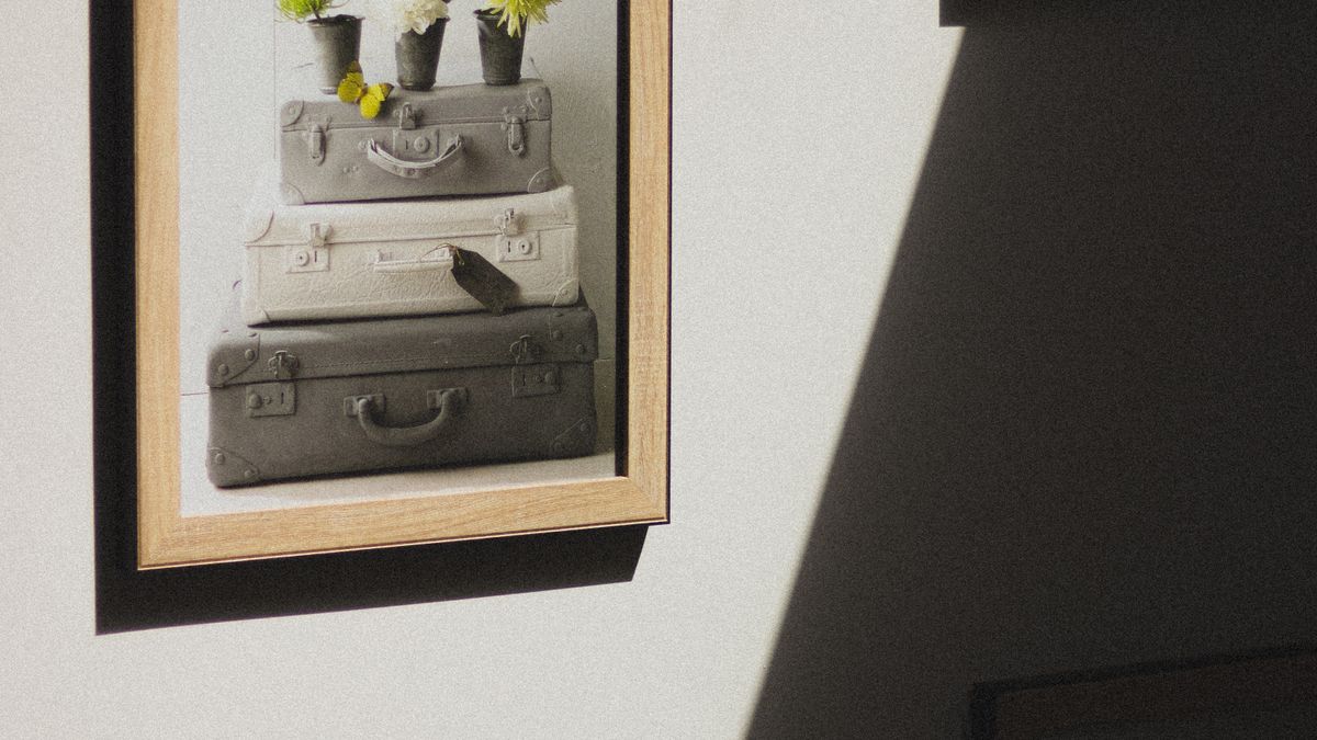 Framed artwork on a wall crossed by light and shadows